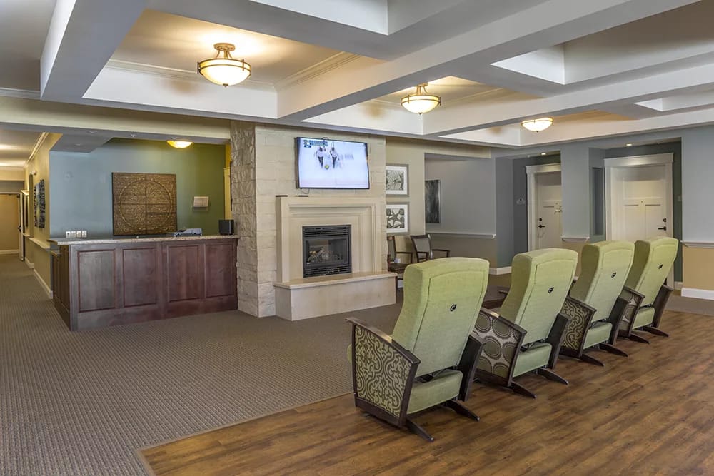 Comfortable seating area with a fireplace and television in a senior living facility.