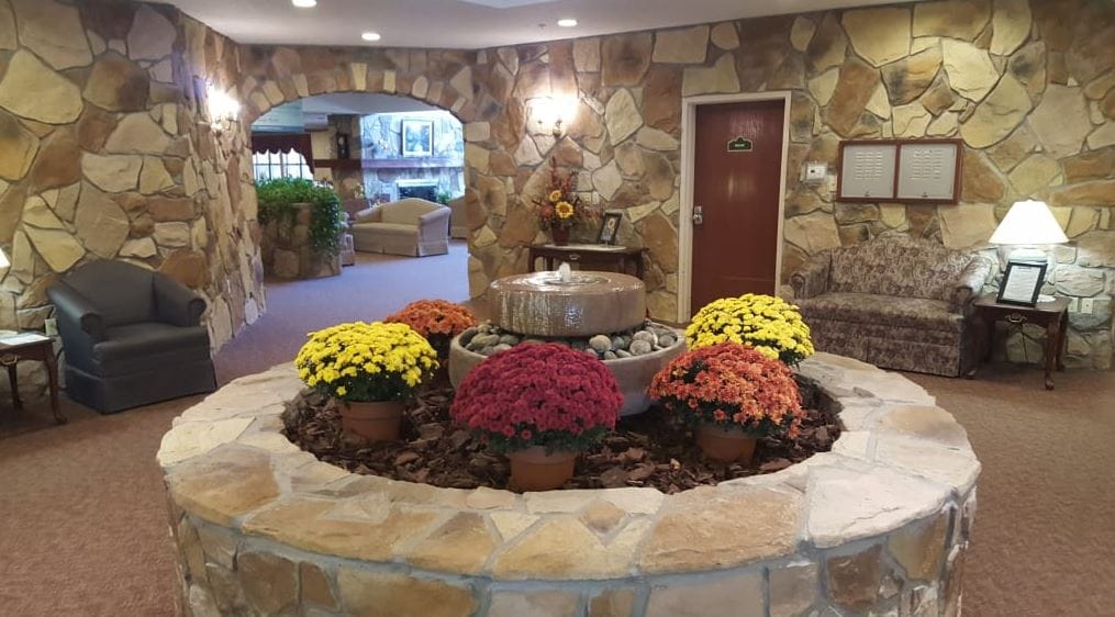 Welcoming lobby with a stone fountain and colorful flowers