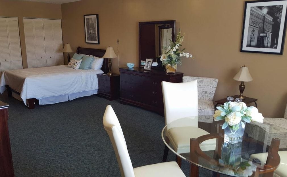 Spacious bedroom with a bed, dresser, and dining table