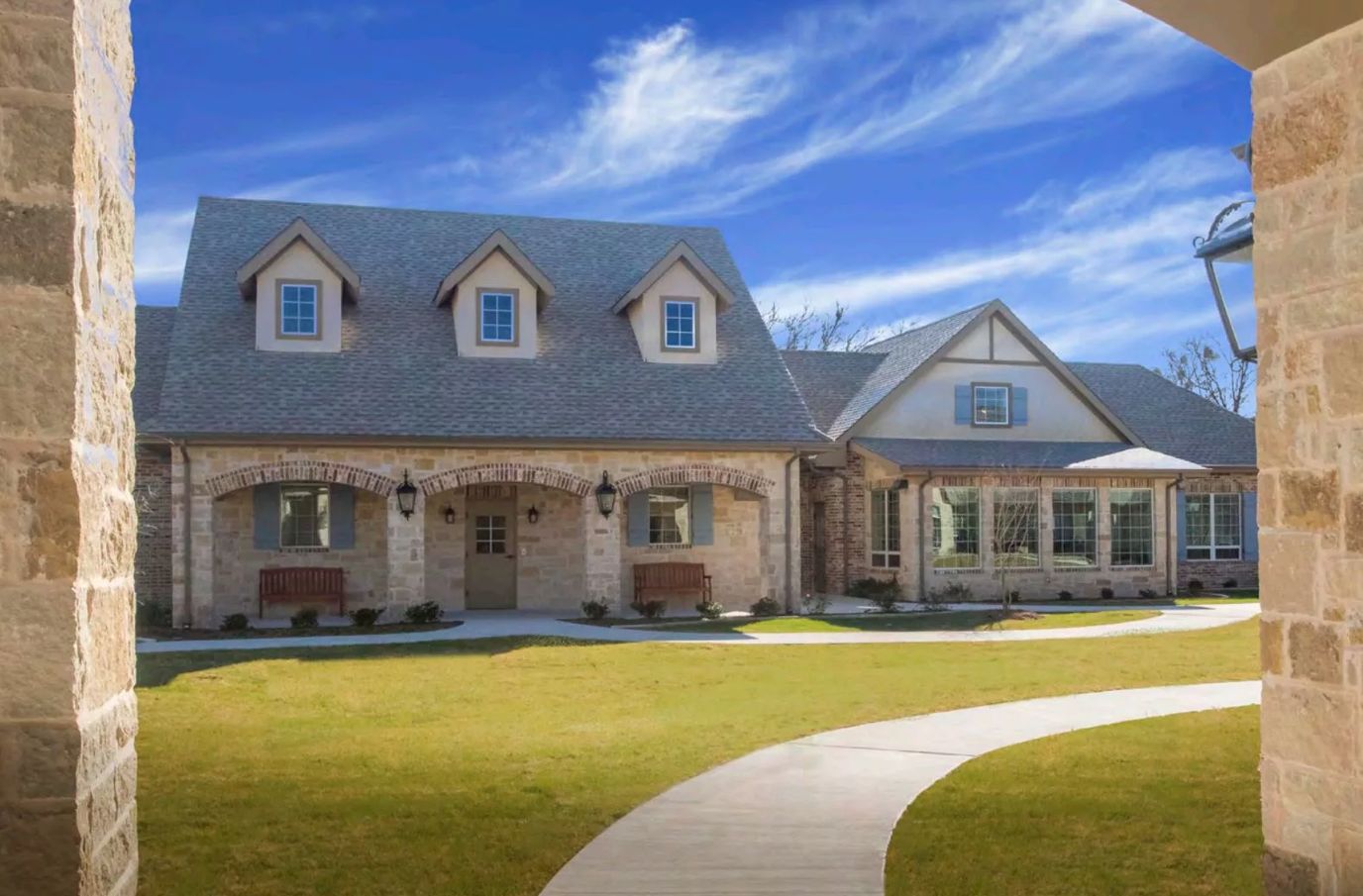 Exterior of a senior living facility with stone architecture and landscaped grounds.