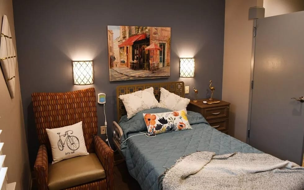 A cozy bedroom featuring a bed, armchair, and decorative artwork.