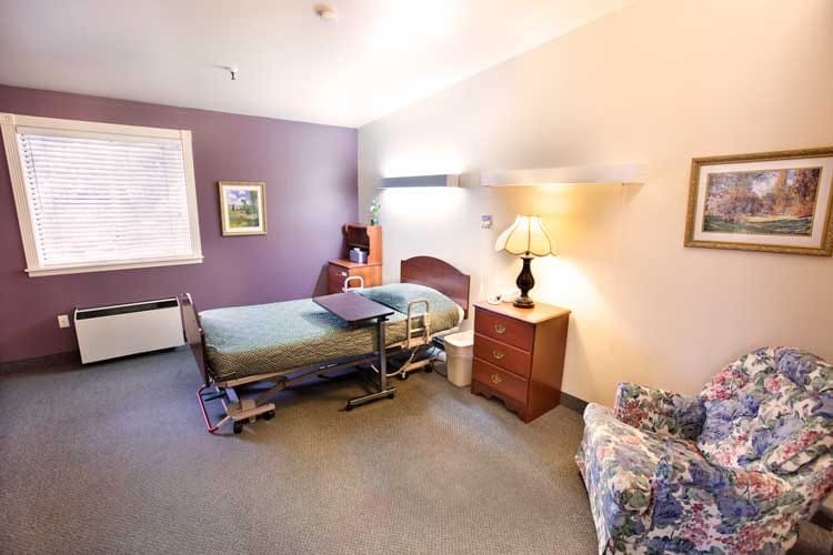 Comfortable bedroom with a hospital bed, nightstand, and chair.