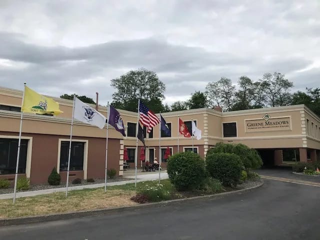 Exterior view of Greene Meadows Nursing with flags in front.