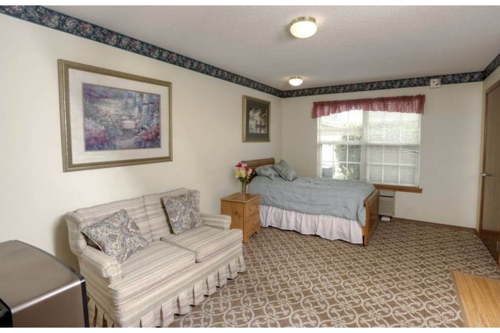 A cozy bedroom featuring a bed, sofa, and window.