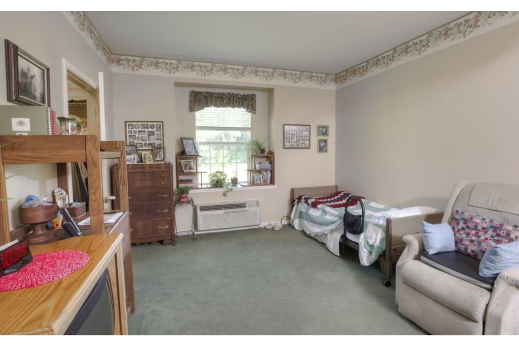 A cozy and well-decorated room with a bed, chair, and window.