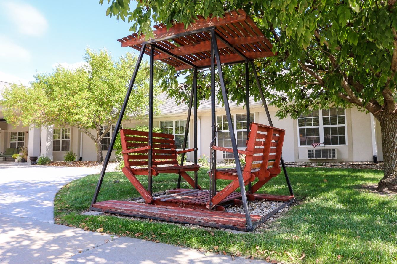 A red swing set with two seats in a landscaped area