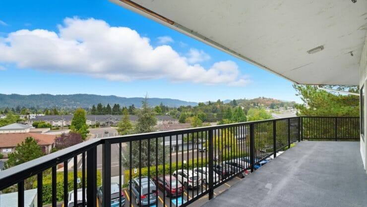 Scenic view from a balcony with mountains and trees.