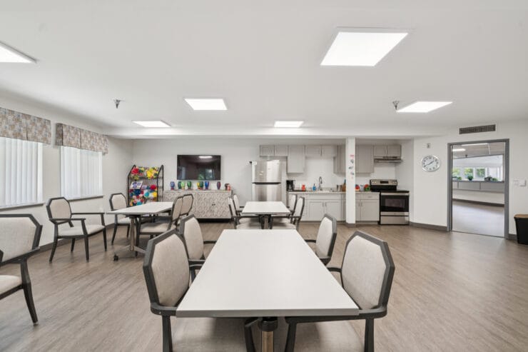 Common area with tables and chairs in a bright room.