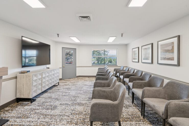 Empty waiting area with gray chairs and TV