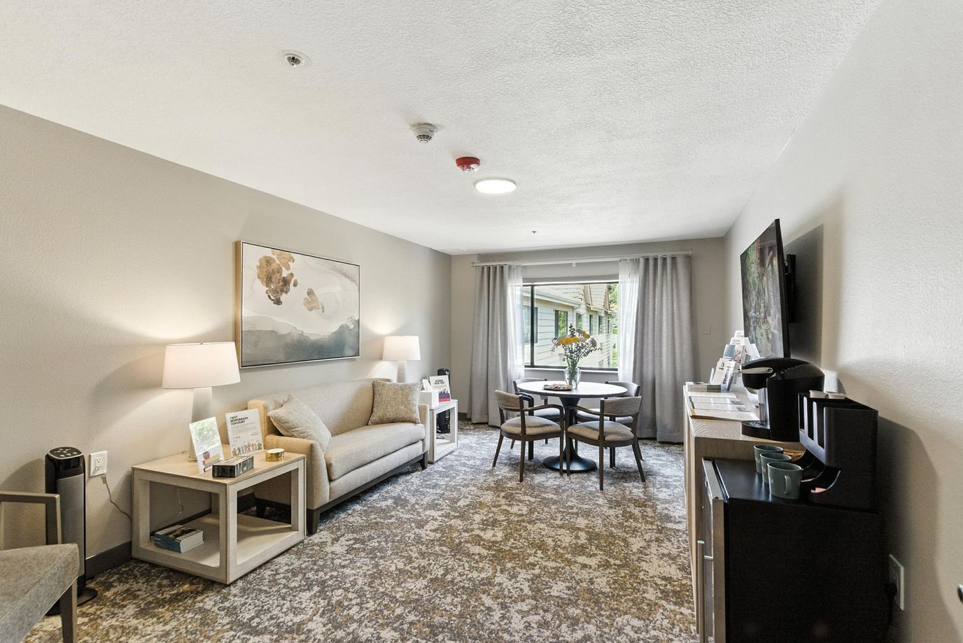 A comfortable living room with a sofa, dining table, and a view of the outdoors.