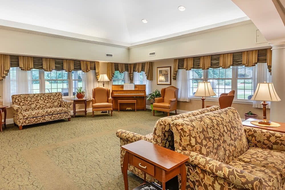 Comfortable living room with seating and a piano at Brookdale Portage