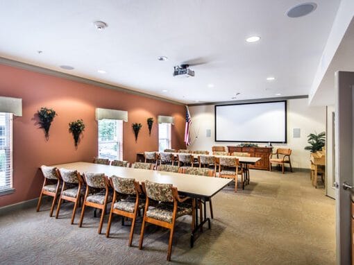 Well-lit common area with seating and a presentation screen