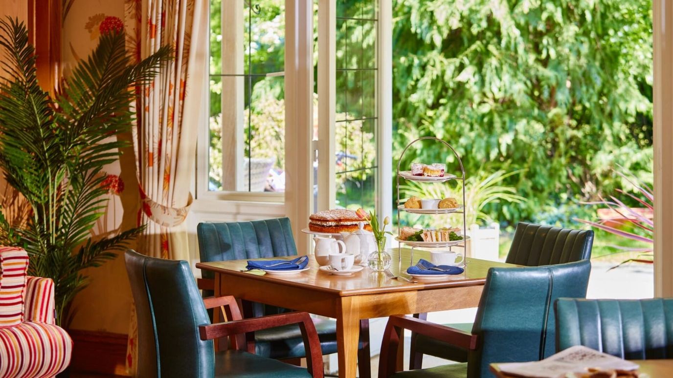 A dining area with an afternoon tea setup by the window