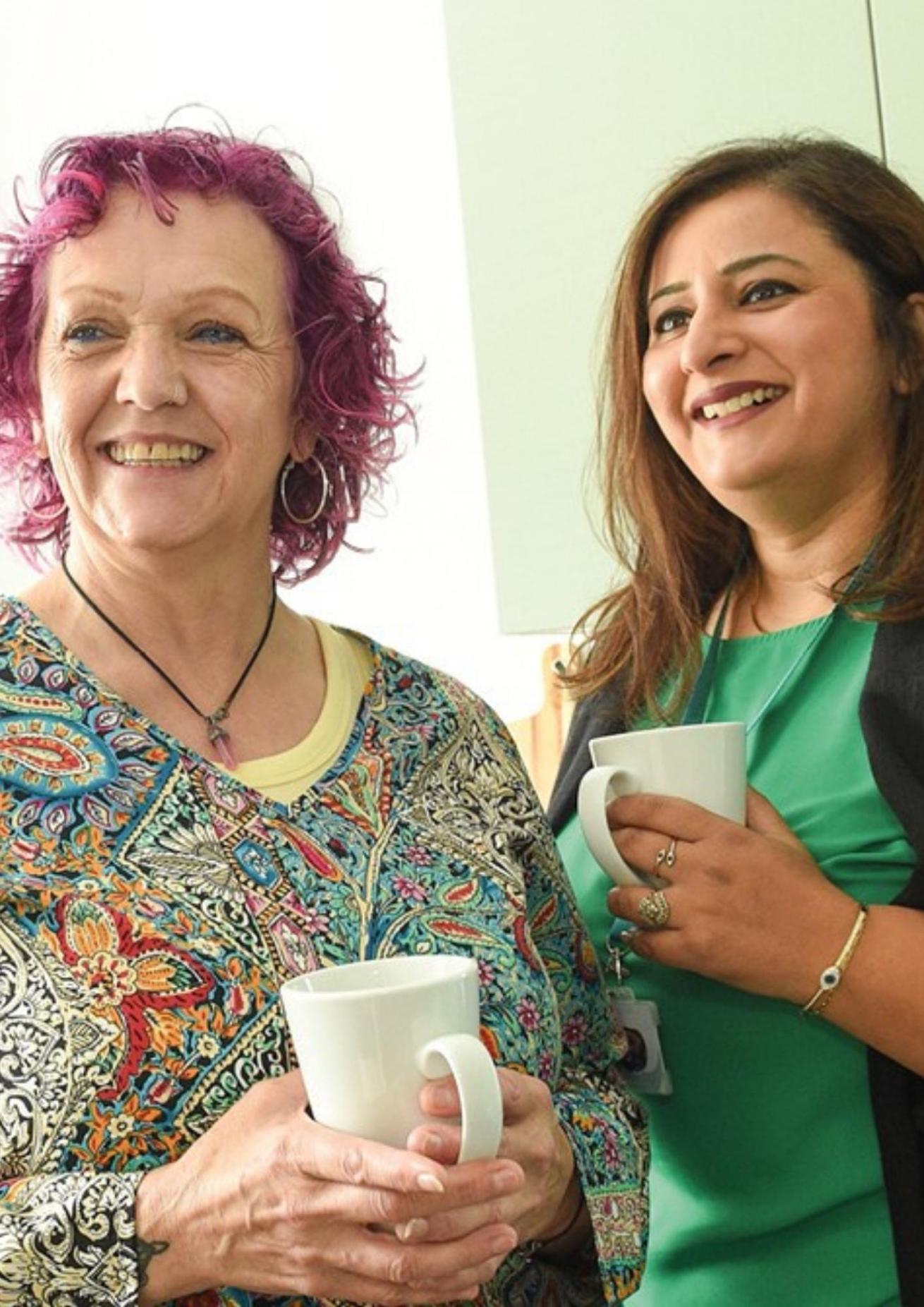 Two smiling women holding coffee cups