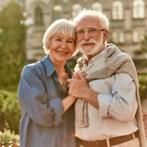 Elderly couple smiling in a garden setting