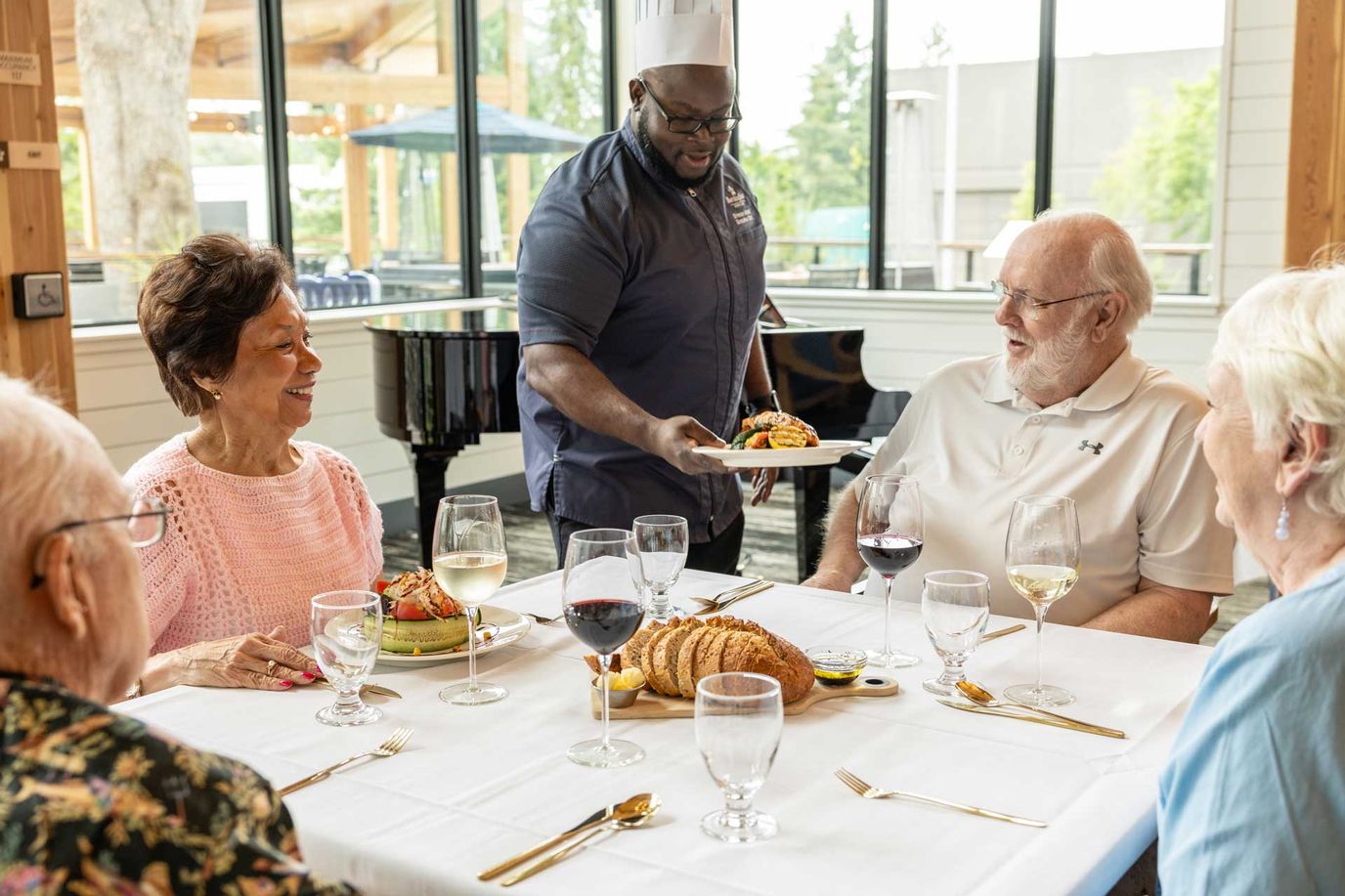 Residents enjoying a meal at a dining table with staff serving food