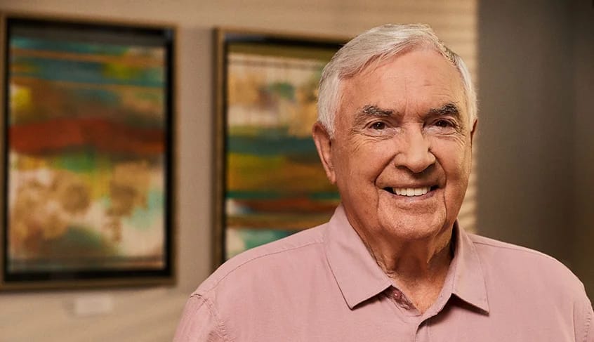 Senior man smiling in a decorated interior space.