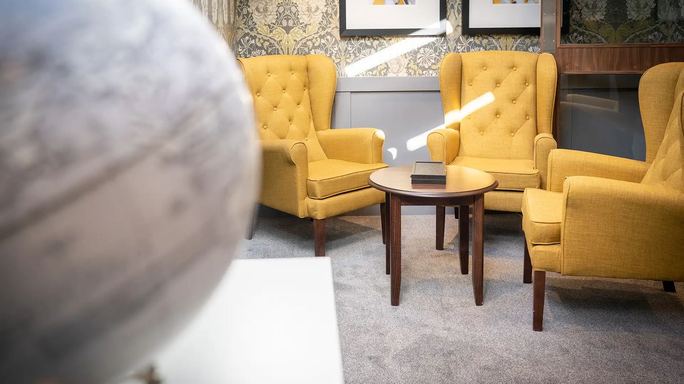 Cozy common area with yellow armchairs and a round table.