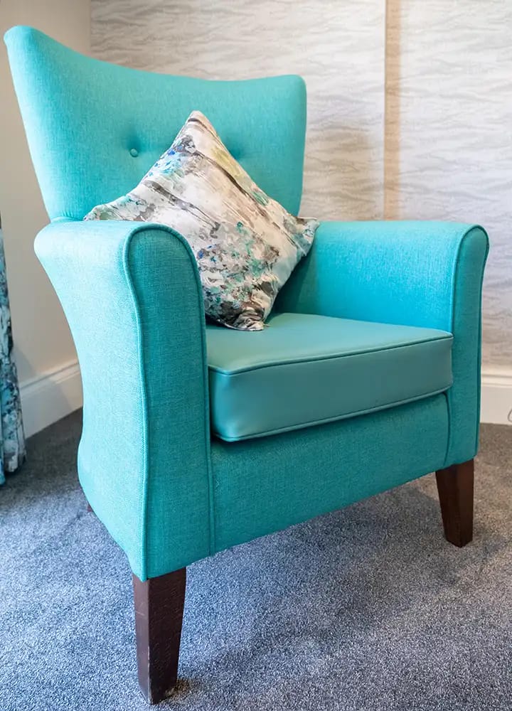 Bright turquoise armchair with a decorative pillow