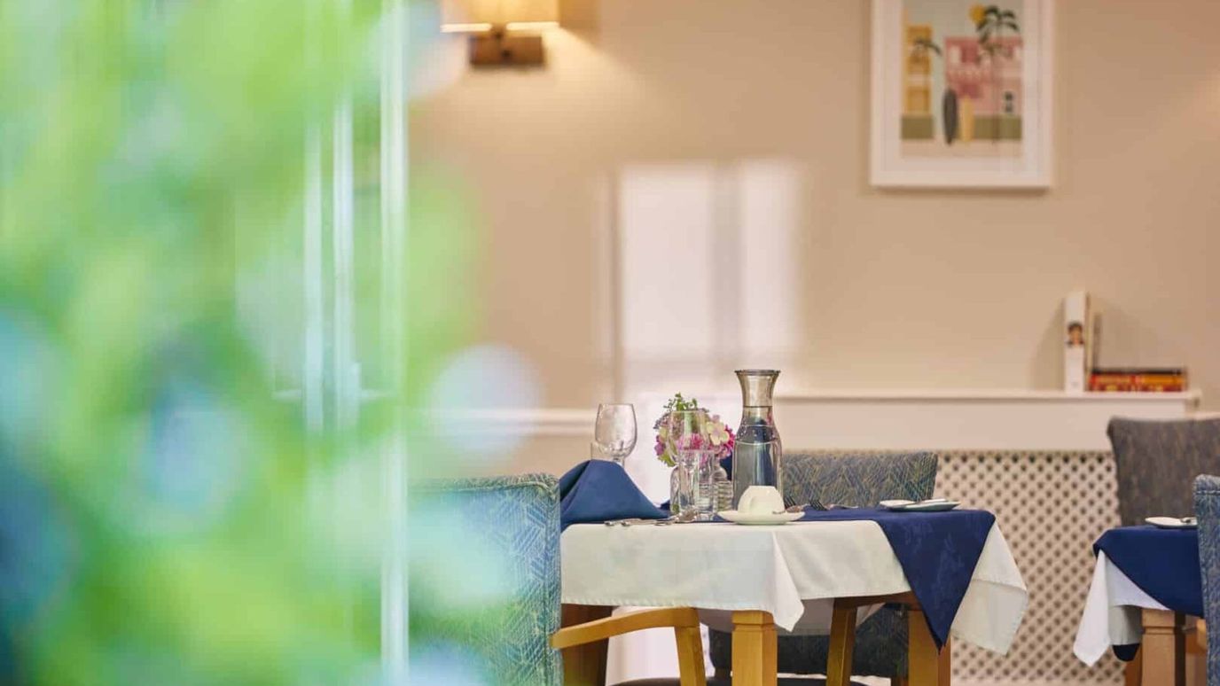 Dining table set with flowers and glassware in a bright room