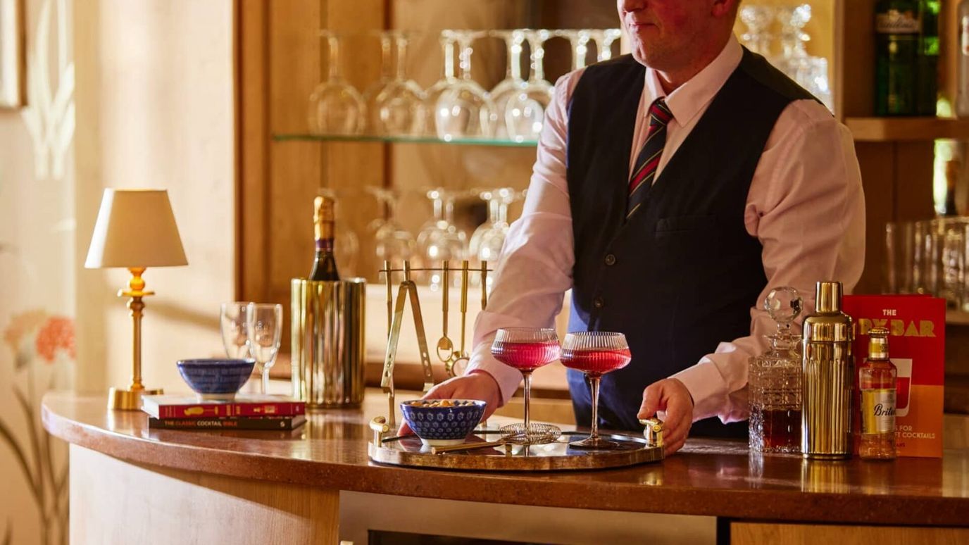 A bartender serving cocktails at a bar area