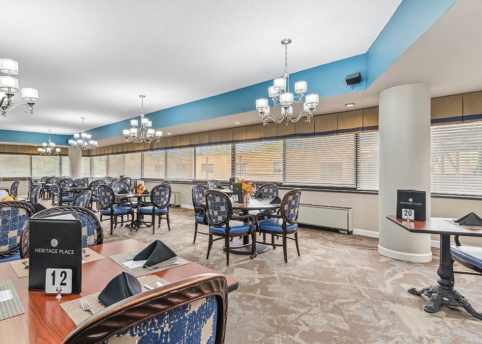 Elegant dining area with tables set for meals at Heritage Place Senior Living.