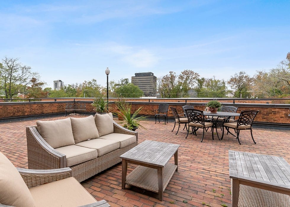 Seating area with couches and tables on a rooftop patio.