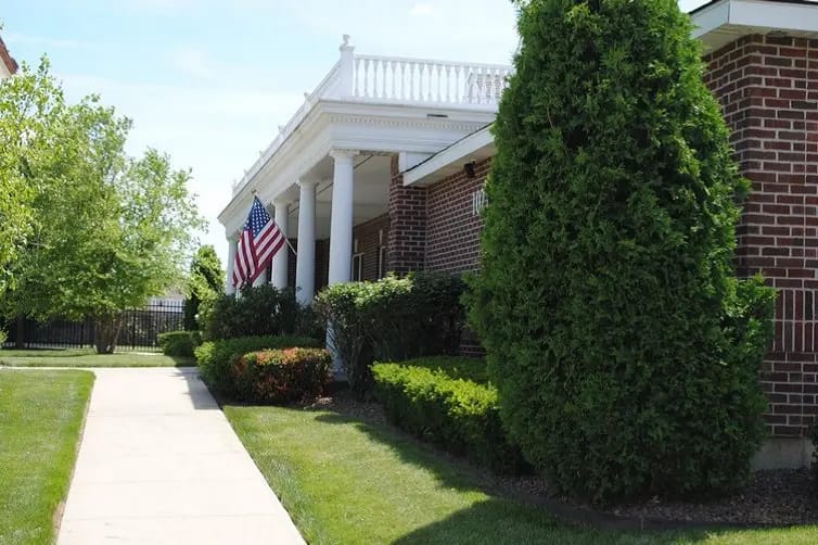 The entrance pathway with landscaped greenery and an American flag.