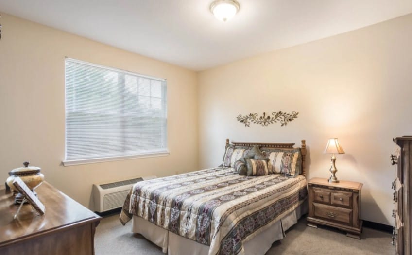 A well-furnished bedroom with a bed, bedside table, and window.
