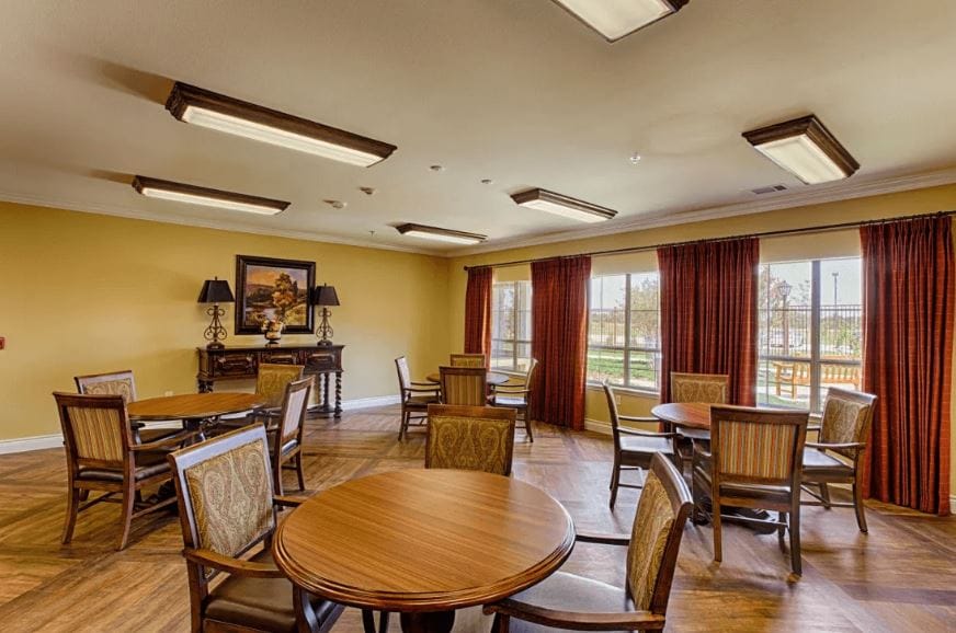 Dining room with wooden tables and chairs, bright windows, and warm decor