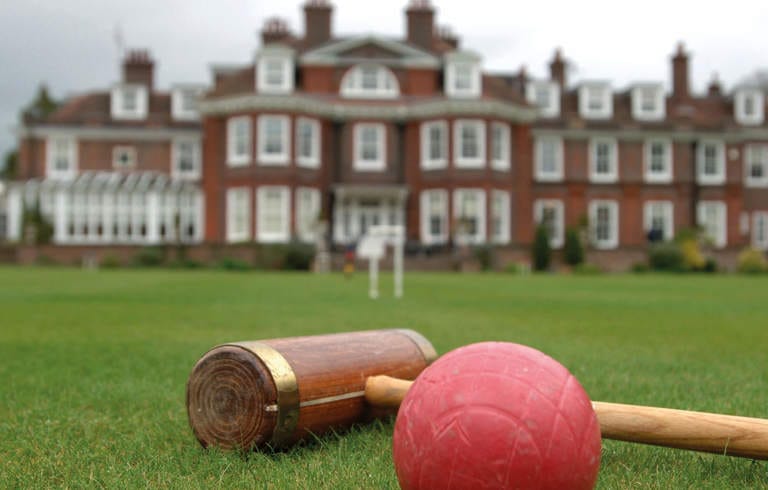 Croquet mallet and ball in front of a large building