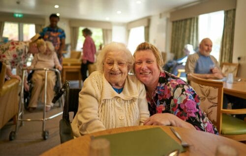 Resident and staff member smiling in a common area