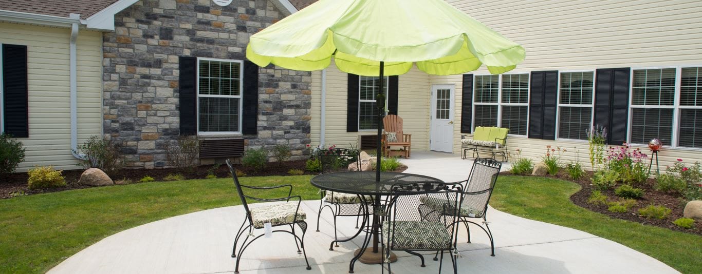 Outdoor seating area with green umbrella and flowers