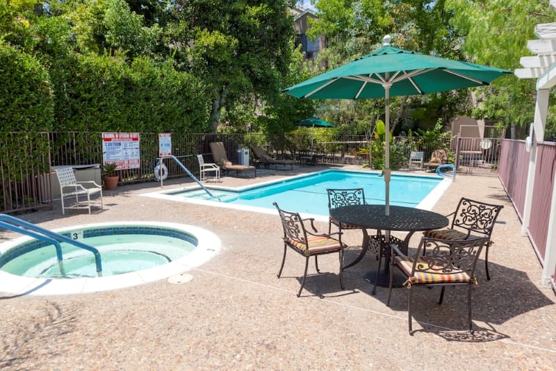 Outdoor pool and hot tub area with seating and umbrellas