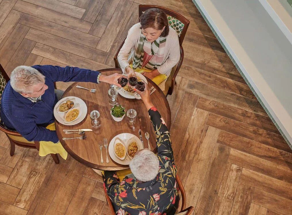 Residents toasting with glasses at a dining table