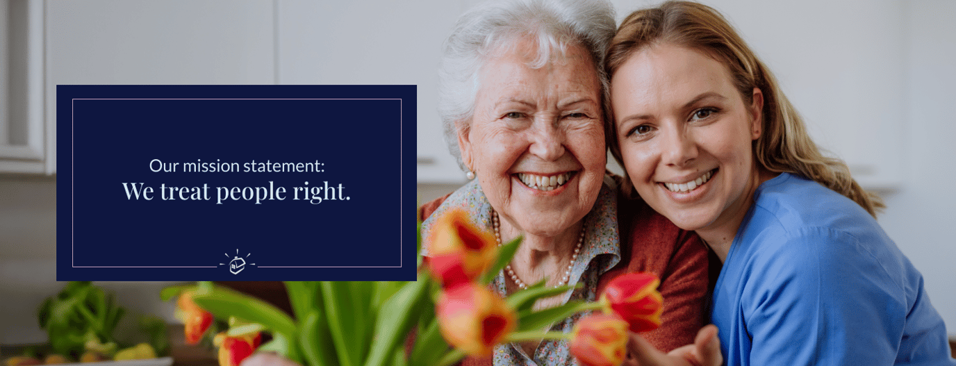 Resident and staff member smiling together indoors.
