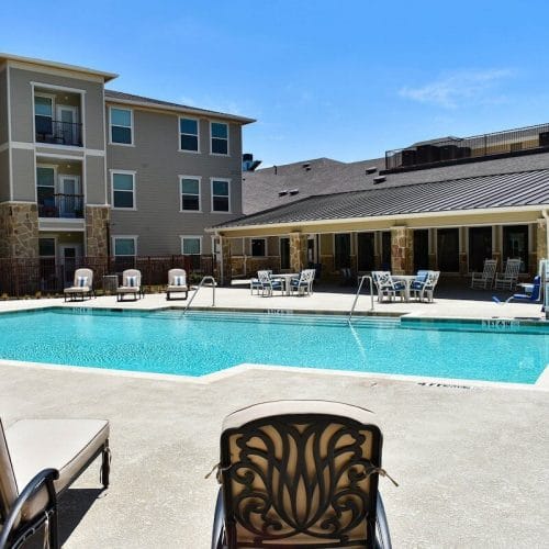 Outdoor pool area with lounge chairs and building in the background