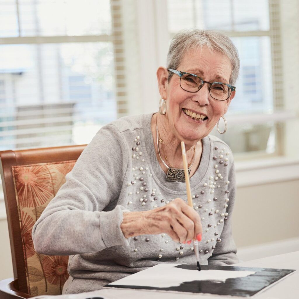 Resident enjoying a painting activity in a bright room
