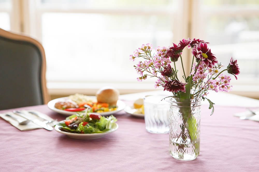 A dining table set with meals and flowers