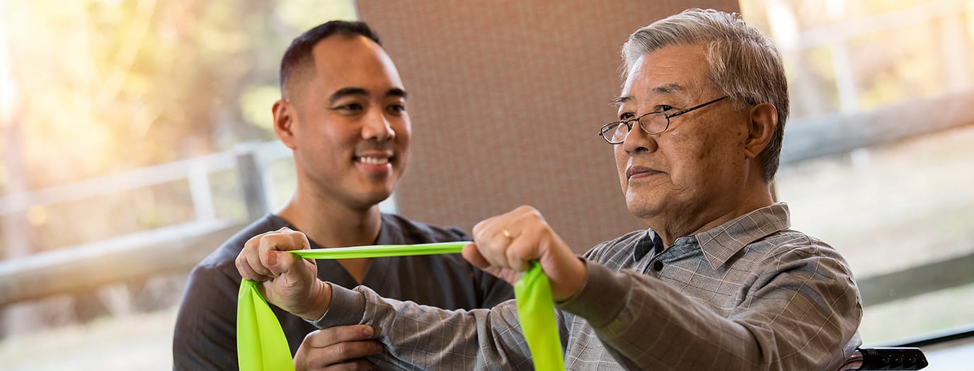A staff member assisting a resident with resistance bands