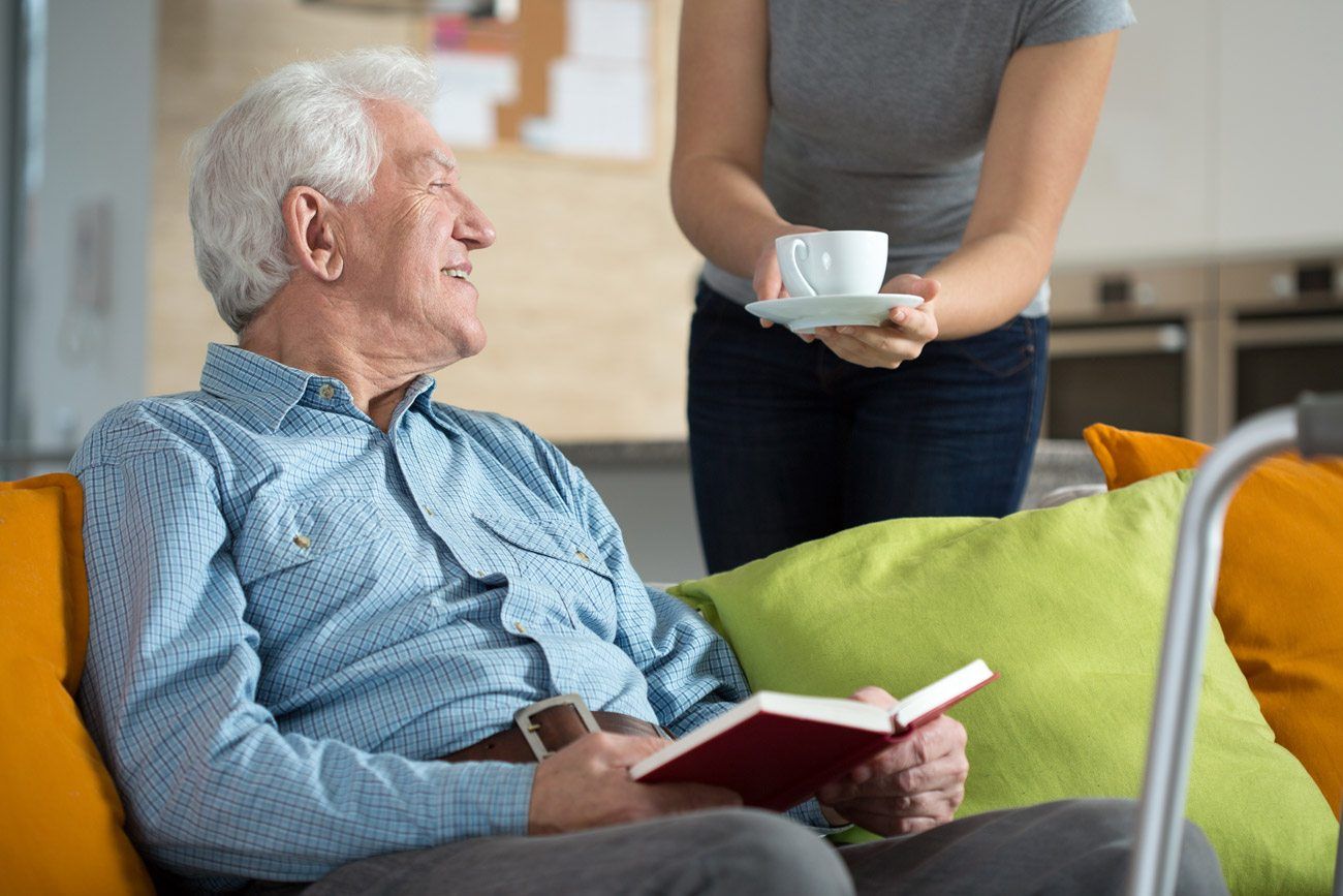 Resident enjoying a book while being served coffee