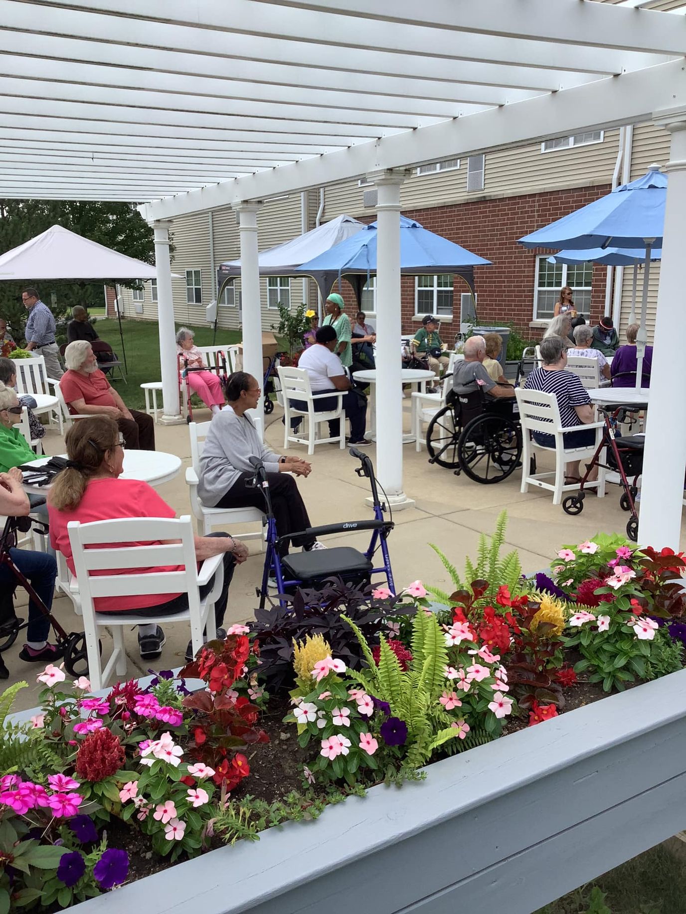 Residents enjoying an outdoor event under a shaded pergola.