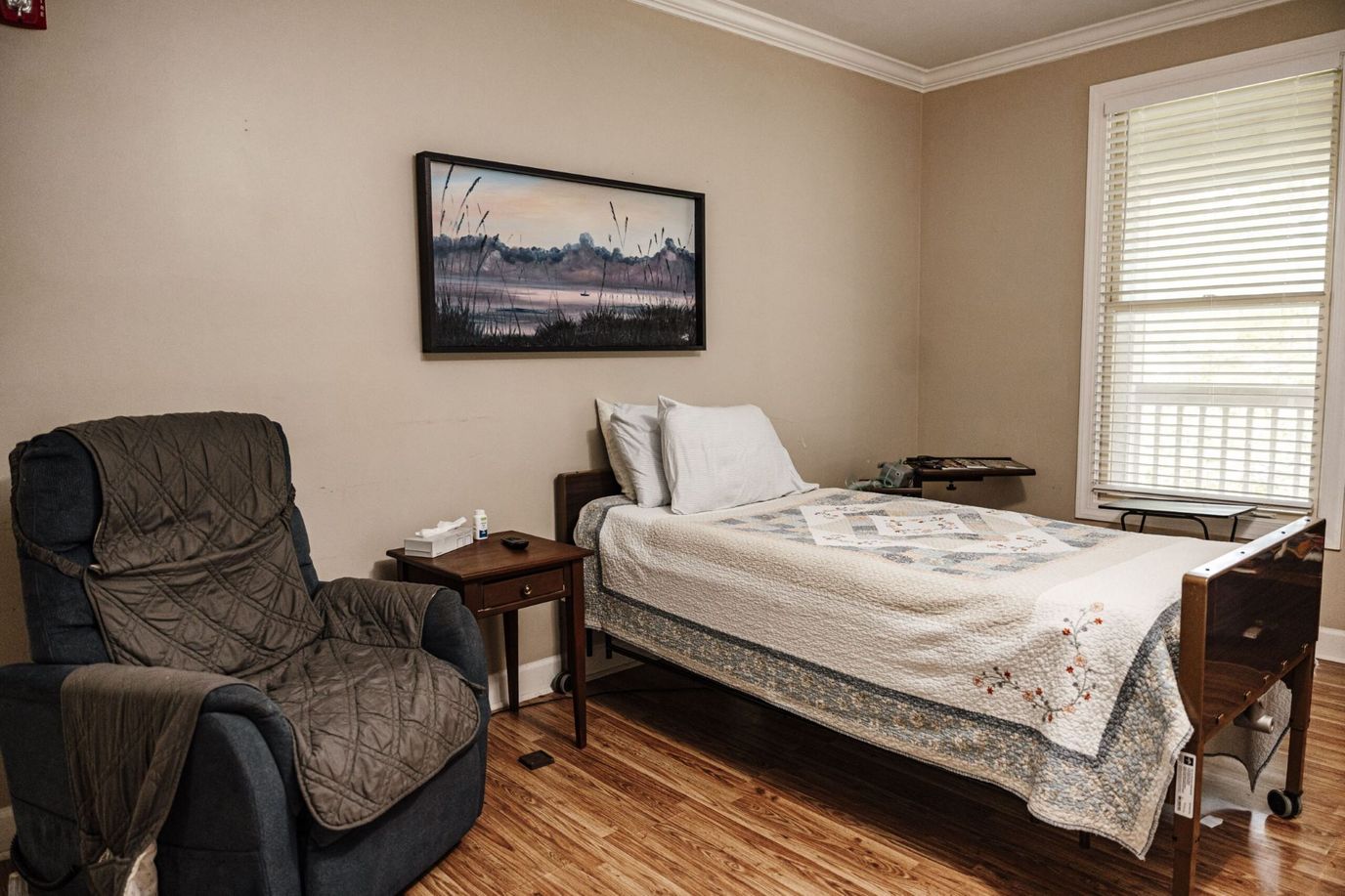 A cozy bedroom with a bed, armchair, and a window.