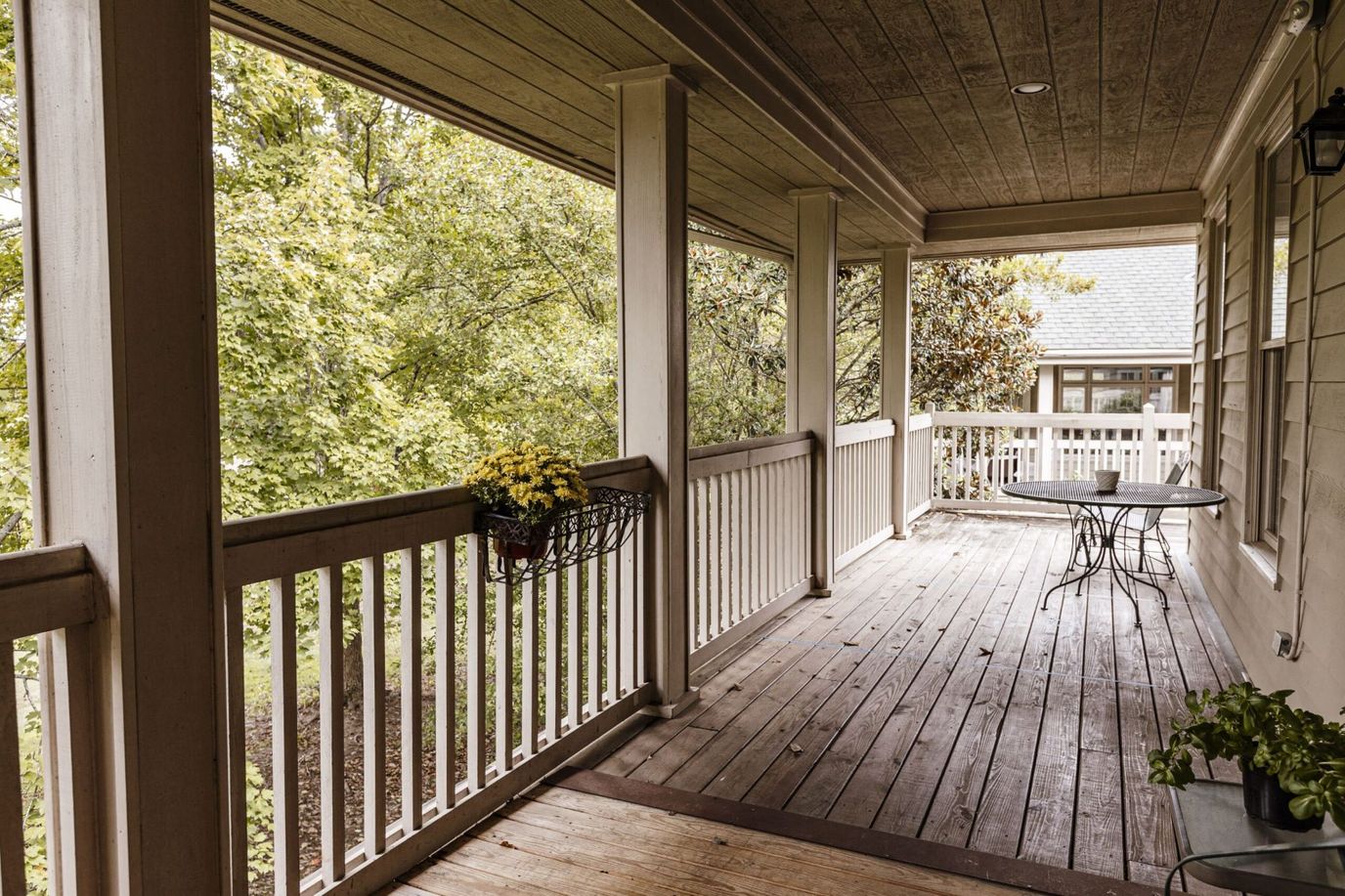 Covered porch with table and flowers overlooking trees
