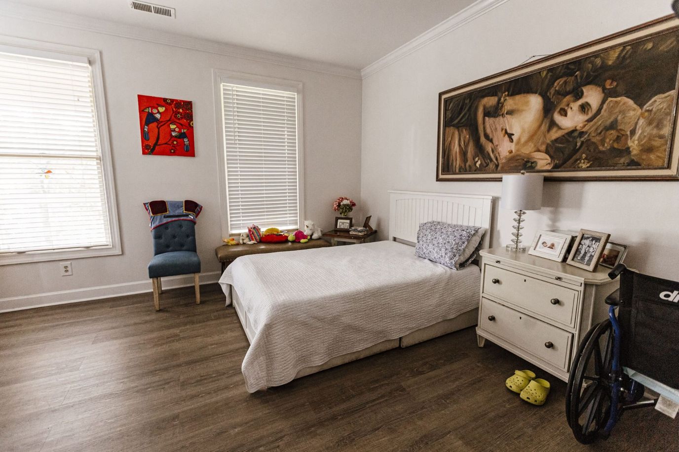 A furnished room featuring a bed, chair, and decorative art