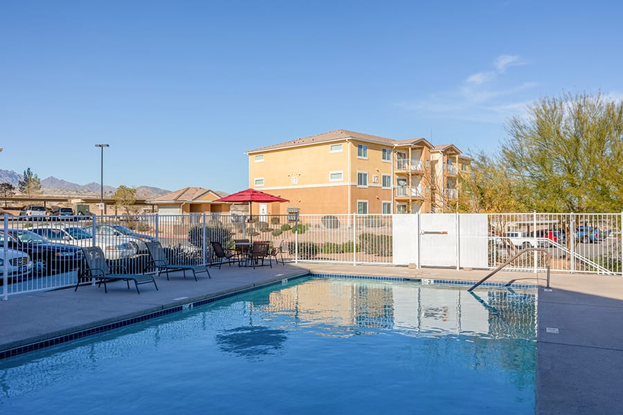 Swimming pool surrounded by lounge chairs and an umbrella at Vintage at Laughlin.