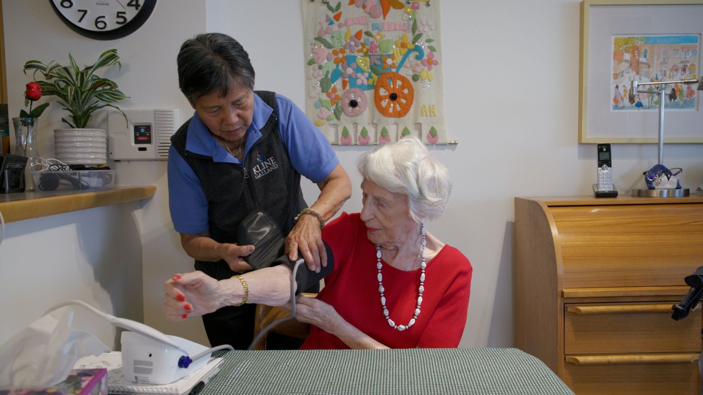 Nurse taking a resident's blood pressure in a common area