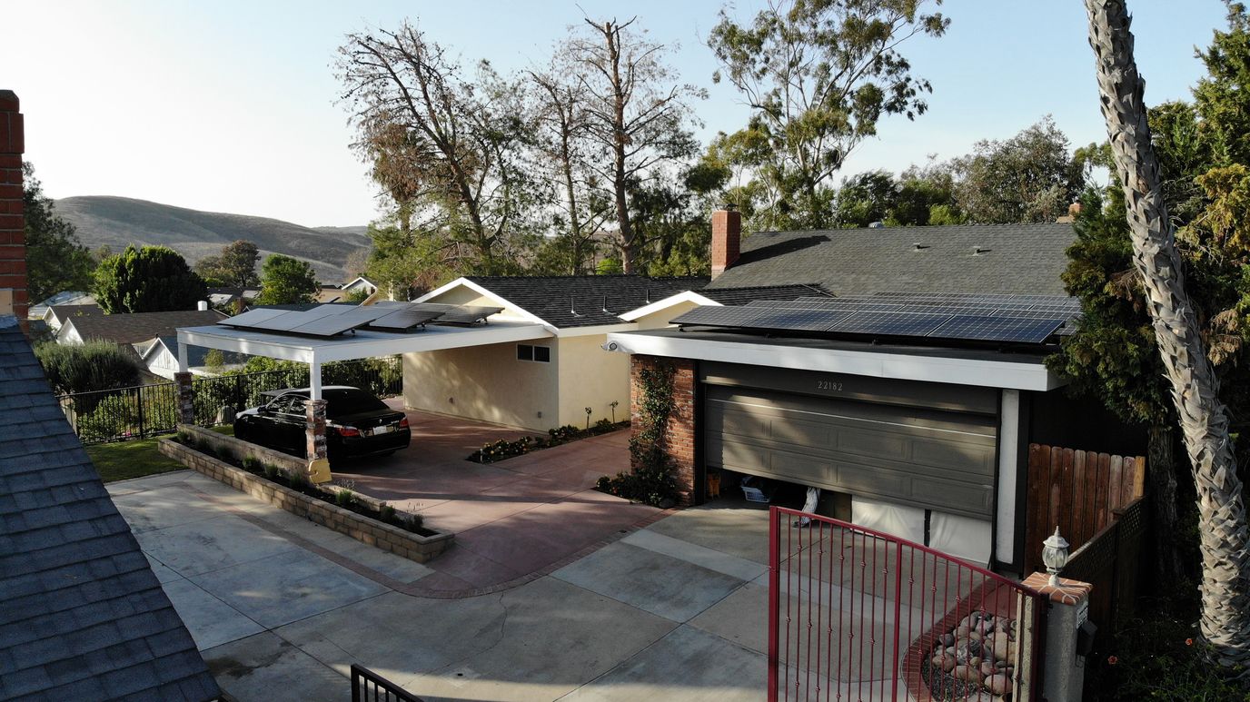 Aerial view of a house with solar panels and carport