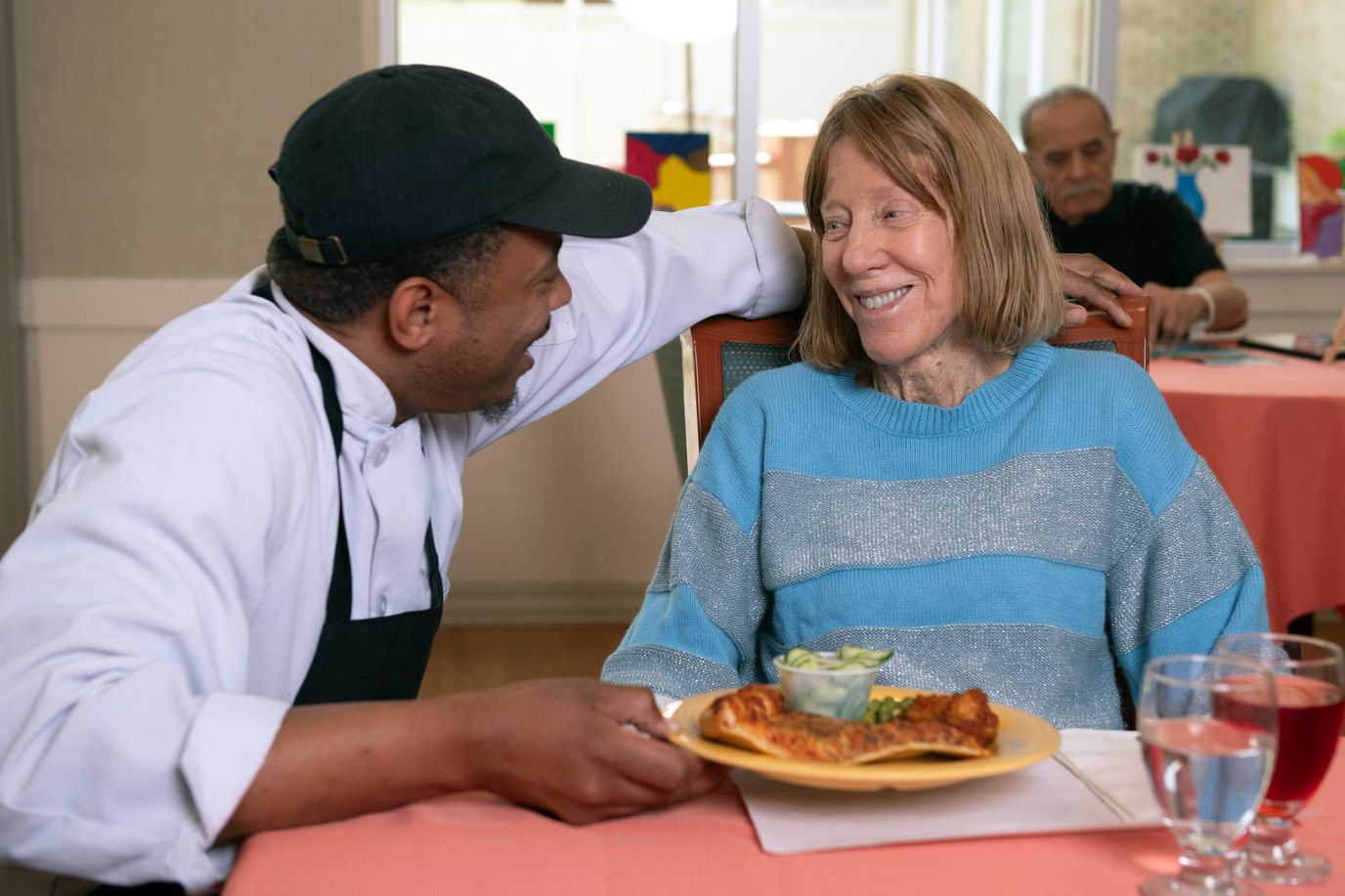 Staff member serving a meal to a resident in the dining room