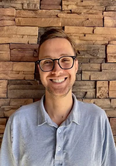 Smiling staff member in front of a stone wall